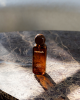 Amber-colored bottle with 'nemah' branding on a marble surface