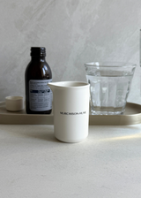 Ceramic measuring cup with medicine bottle and glass of water