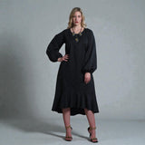 Women's Aphrodite Black Leopard Jacquard Dress styled with a gold necklace, black clutch and gold chain heels for a chic, coordinated look. Gray background.