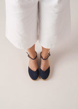 Top view of navy canvas ankle-strap wedge espadrilles with a natural jute platform on model