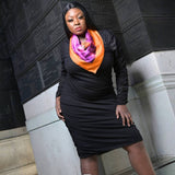 Woman wearing a black dress and colorful Bird of Paradise Pink Purple Silk Scarf standing against a stone wall.