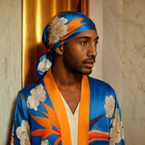 Man wearing a Colorful Bird of Paradise White Blue Cherry Blossom Silk kimono garment with abstract patterns and matching headscarf against a neutral background