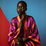 Person wearing a vibrant, multicolored Bird of Paradise Pink Purple Silk Kimono against a blue and red background