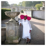 Women's Plus Size Aphrodite White Holiday Resort Dress with hoodie and white undergarment, paired with a pink sunhat, pink clutch, and black heels.