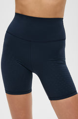 Model wearing the L’Original Bike Short in navy blue, made from OEKO-TEX® certified compression fabric featuring Elastique’s MicroPerle® technology to promote lymphatic drainage, enhance circulation, reduce fatigue, and smooth the skin.