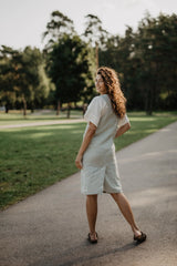 Back Of Women Wearing A Green Mint Linen Apron Dress With White Top