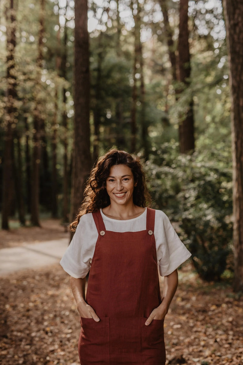 Front Of Women Wearing A Red Linen Apron Dress With White Top