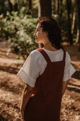 Back Of Women Wearing A Red Linen Apron Dress With White Top