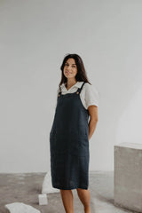 Front Of Women Wearing A Black Linen Apron Dress In A Gallery