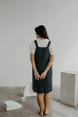 Back Of Women Wearing A Black Linen Apron Dress