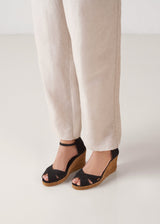 Model wearing black canvas ankle-strap wedge espadrilles with a natural jute sole