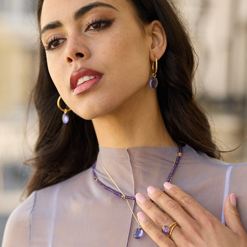 Our Eden Gold Hoop Earrings are handmade in various sizes and are bejewelled with a removable Amethyst gemstone charm. Match them with our Eden necklaces for a complete look!