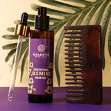 Saabuni Jasmine hair oil with a dropper and wooden comb on a purple surface with green leaves in the background