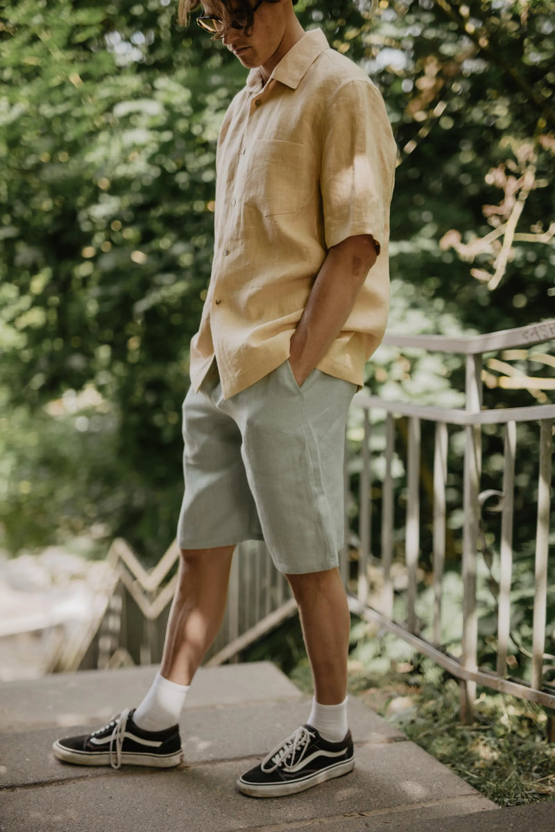 Man Walking Down Stairs Wearing Sage Green Linen Shirt And Mustard Short Sleeved Shirt