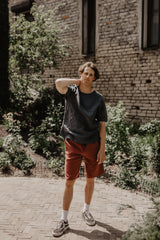 Man In Garden Wearing A Black Oversized Linen T-Shirt and Terracotta Shorts