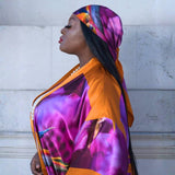 Woman wearing a colorful Bird of Paradise Pink Purple Silk Scarf  and Kimono against a light-colored wall.