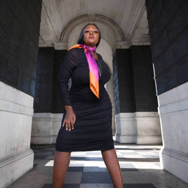 Woman in a black dress with a colorful  Bird of Paradise Pink Purple Silk Scarf standing in an architectural setting
