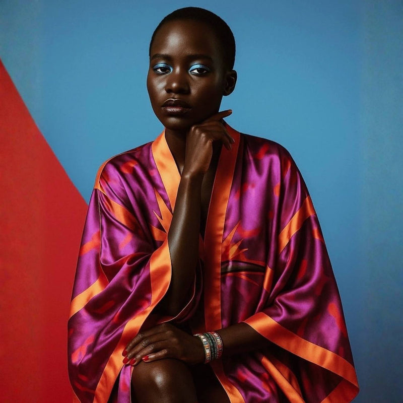 Person wearing a vibrant, multicolored  Bird of Paradise Pink Purple Silk Kimono against a blue and red background