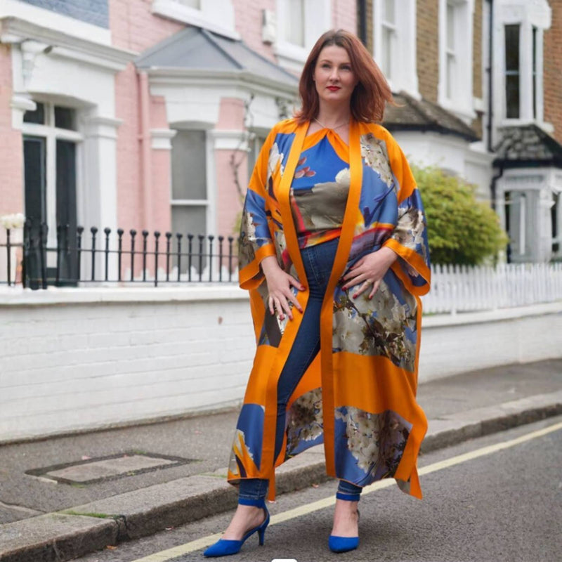 Woman wearing a Colorful Bird of Paradise White Blue Cherry Blossom Silk kimono garment with abstract patterns and matching top against a city background