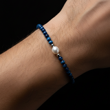 Man's wrist wearing Blue Tigers Eye Pearl Bracelet - black background