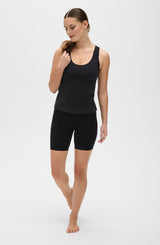 Model wearing the L’Original Bike Short with matching tank in black, made from OEKO-TEX® certified compression fabric featuring Elastique’s MicroPerle® technology to promote lymphatic drainage, enhance circulation, reduce fatigue, and smooth the skin.