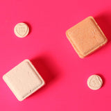 Two square shower steamers and two heart-shaped love heards on a pink background