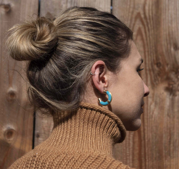 Model wearing an aqua color hoop earring designed by Dilek Sezen