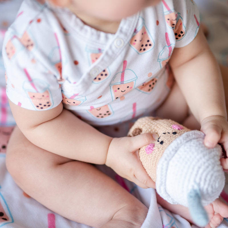 cute baby wearing the wee bean super soft organic cotton onesie bodysuit romper in boba bubble tea and playing with boba bean rattle doll