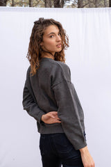 Jolene vee neck handknitted sweater in charcoal grey for women by Paneros Clothing. Featuring side slits, relaxed fit, and a v neckline from 100% cotton. Back and Side View.