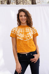 Vintage Cotton Crop Tee in Golden Glow orange color for women by Paneros Clothing. Hand tie-dyed casual top from sustainable cotton. Front View styled with jeans.